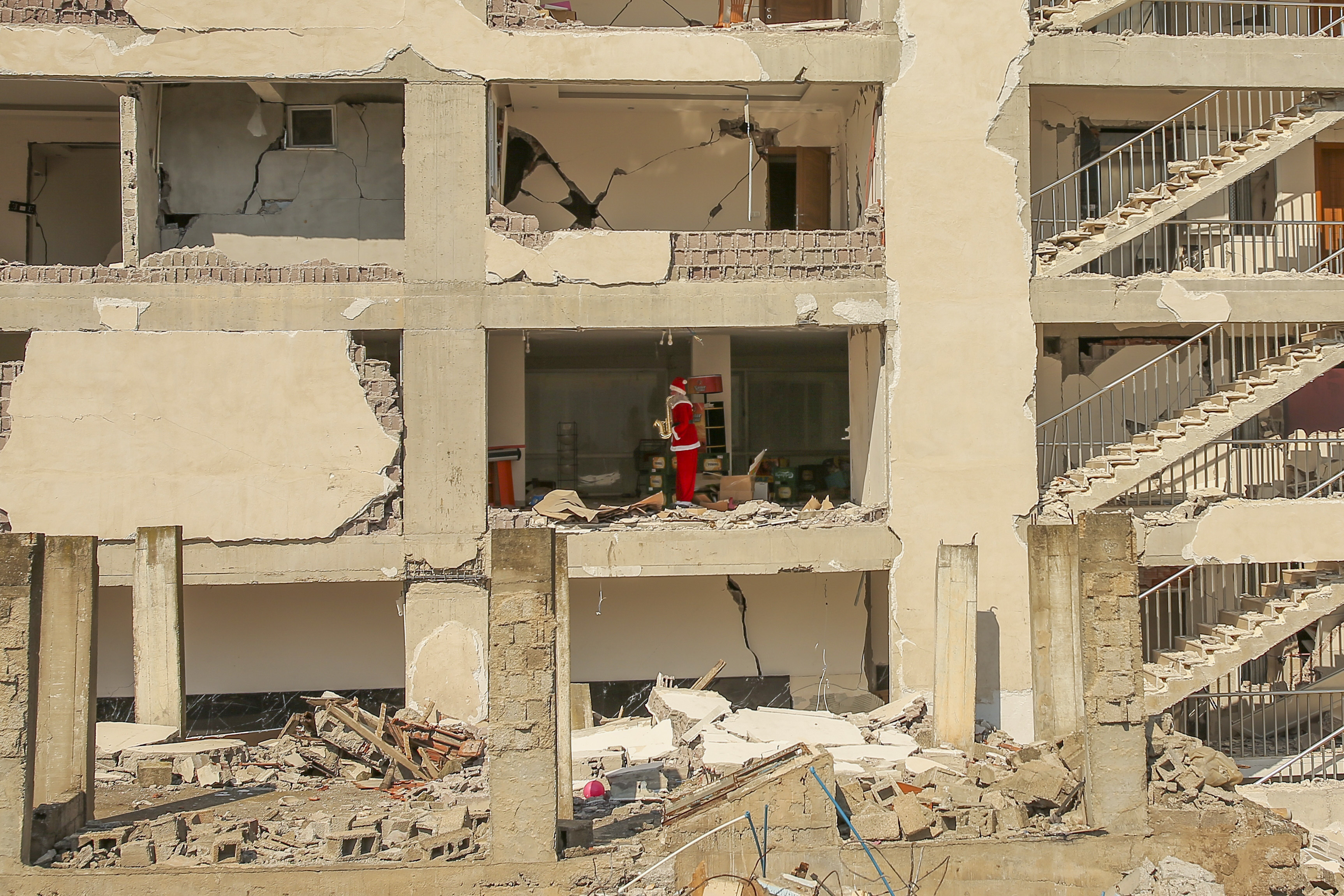 Santa mannequin stands inside destroyed building.