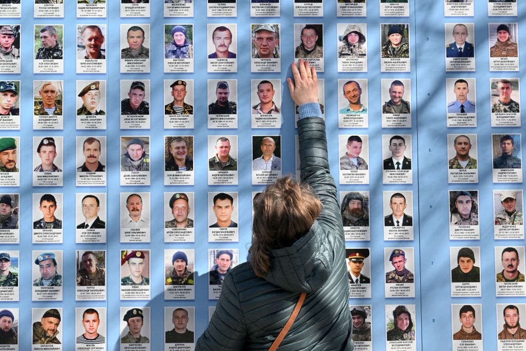 Woman touching photo on memorial wall.