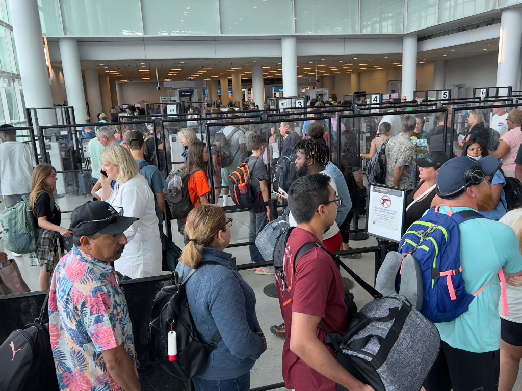 Οι επιβάτες στέκονται στη γραμμή ασφαλείας στο διεθνές αεροδρόμιο Charlotte Douglas.