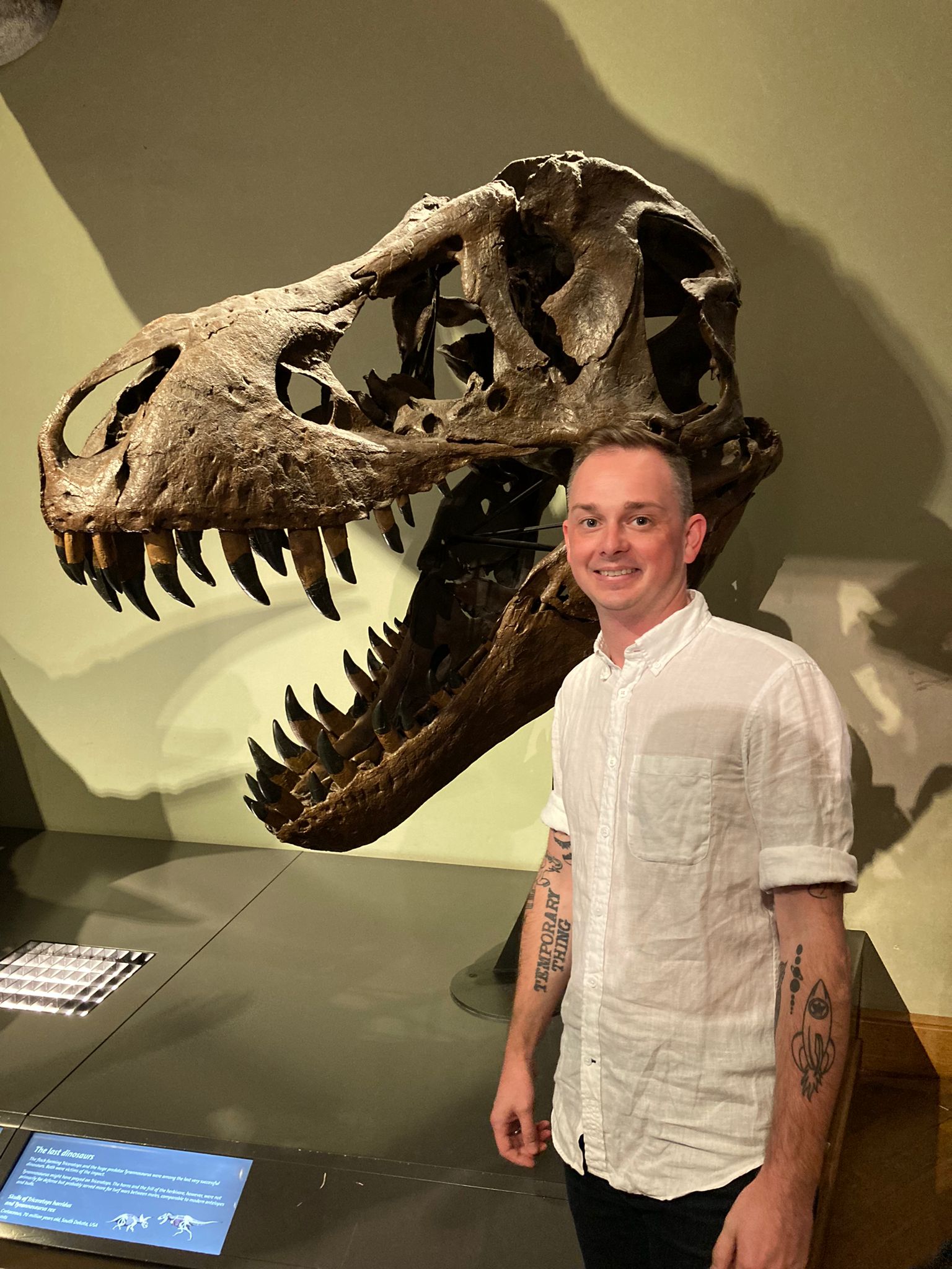 Zach Vanasse stands in front of a dinosaur fossil