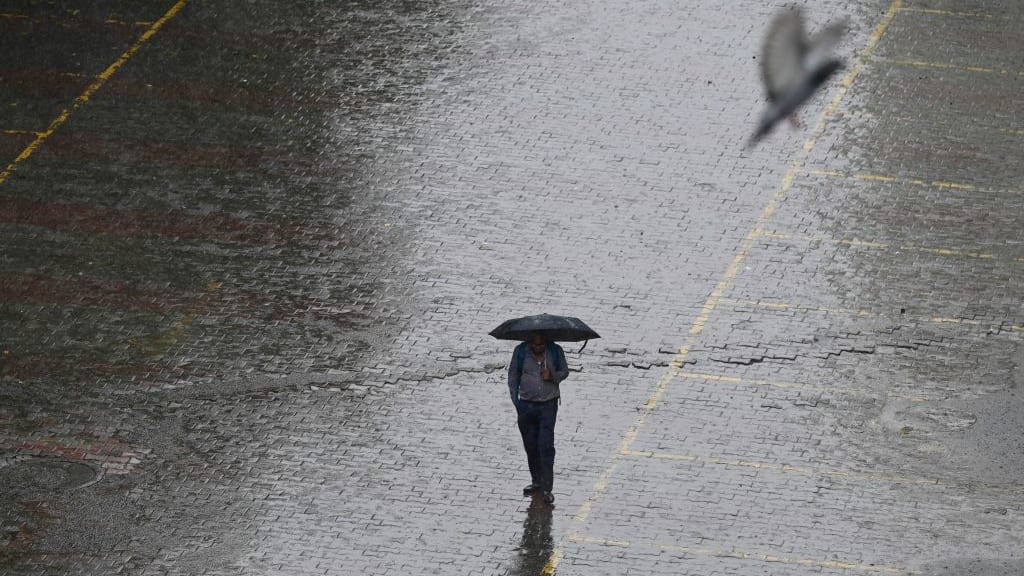 A man with an umbrella walks in the rain.