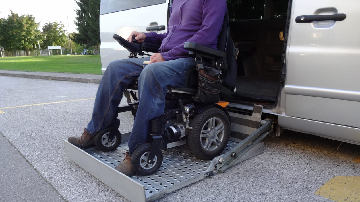 A man in a wheelchair on his car&#039;s lift.