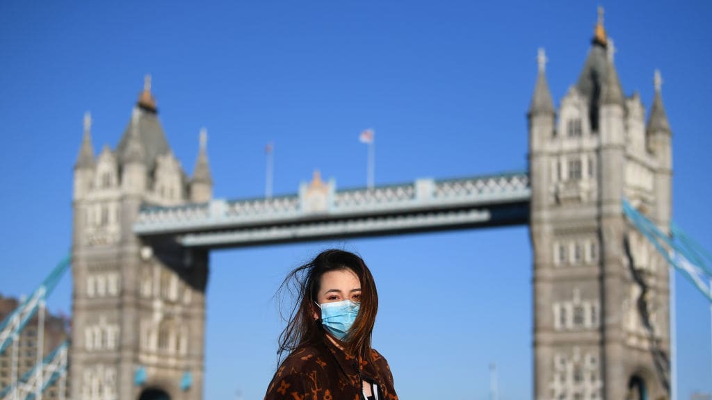 A woman wears a mask by London&#039;s Tower Bridge.