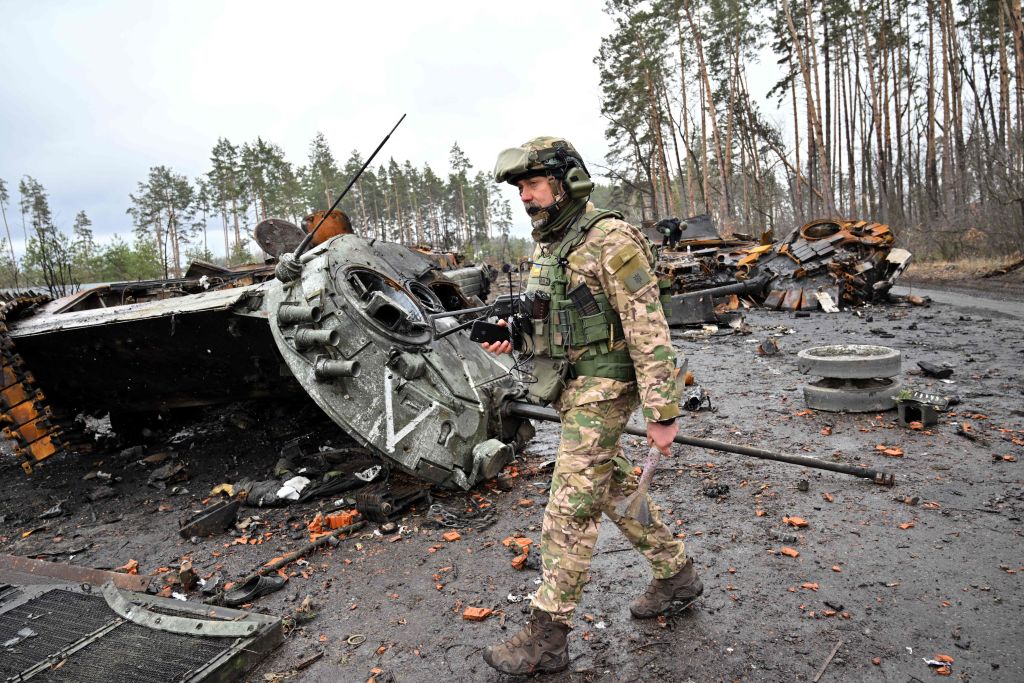 Ukrainian soldier walking past destroyed Russian tanks