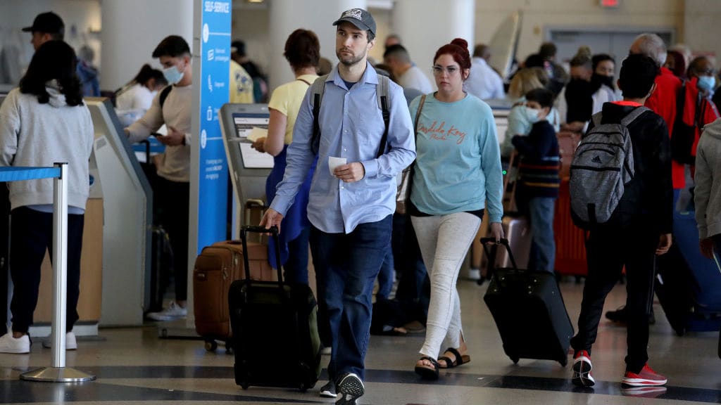 Travelers walk through LAX on Tuesday without masks.