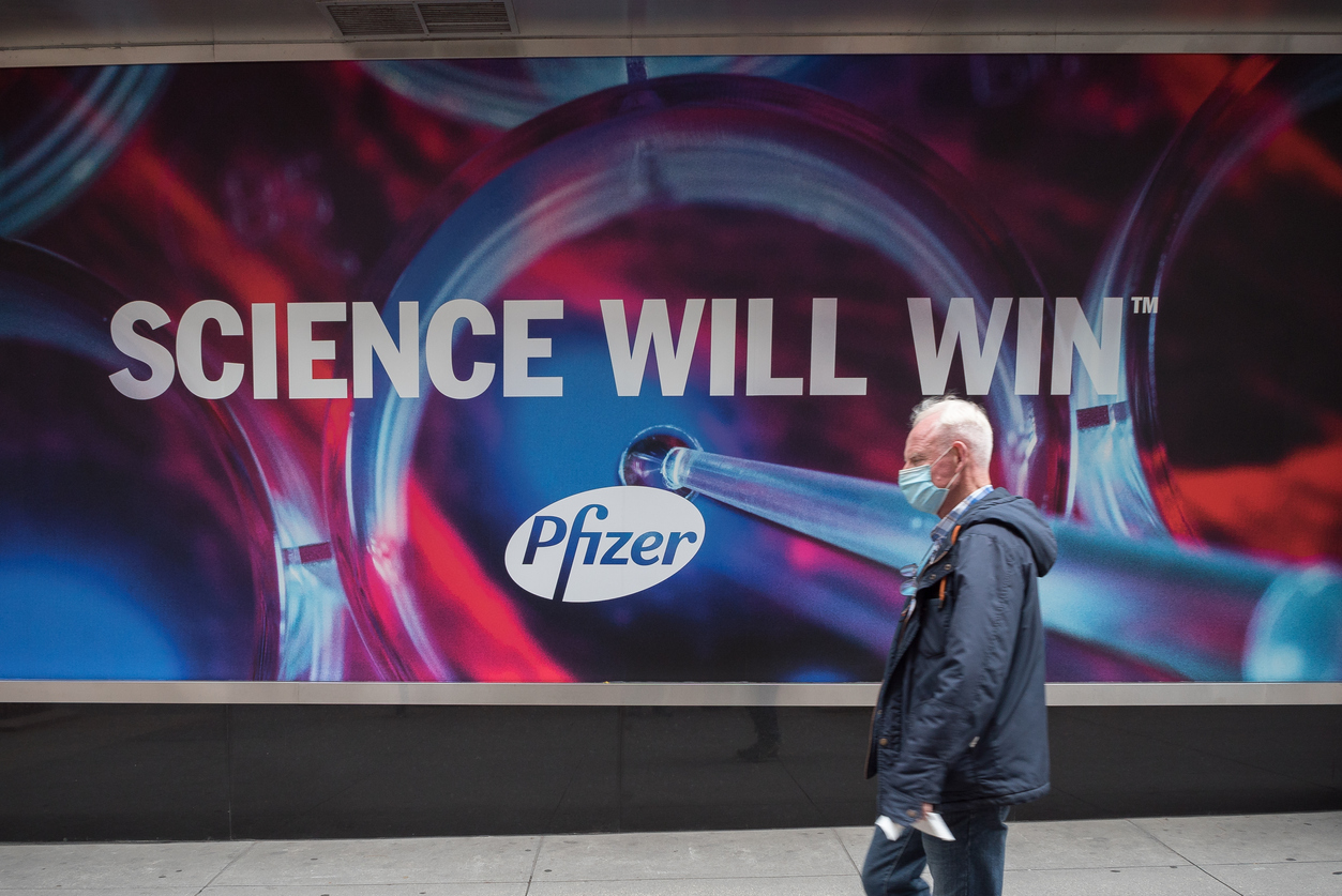 Man walking past Pfizer ad