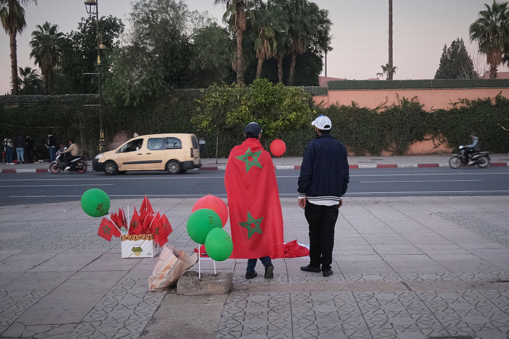 Moroccan soccer fans standing on a sidewalk.