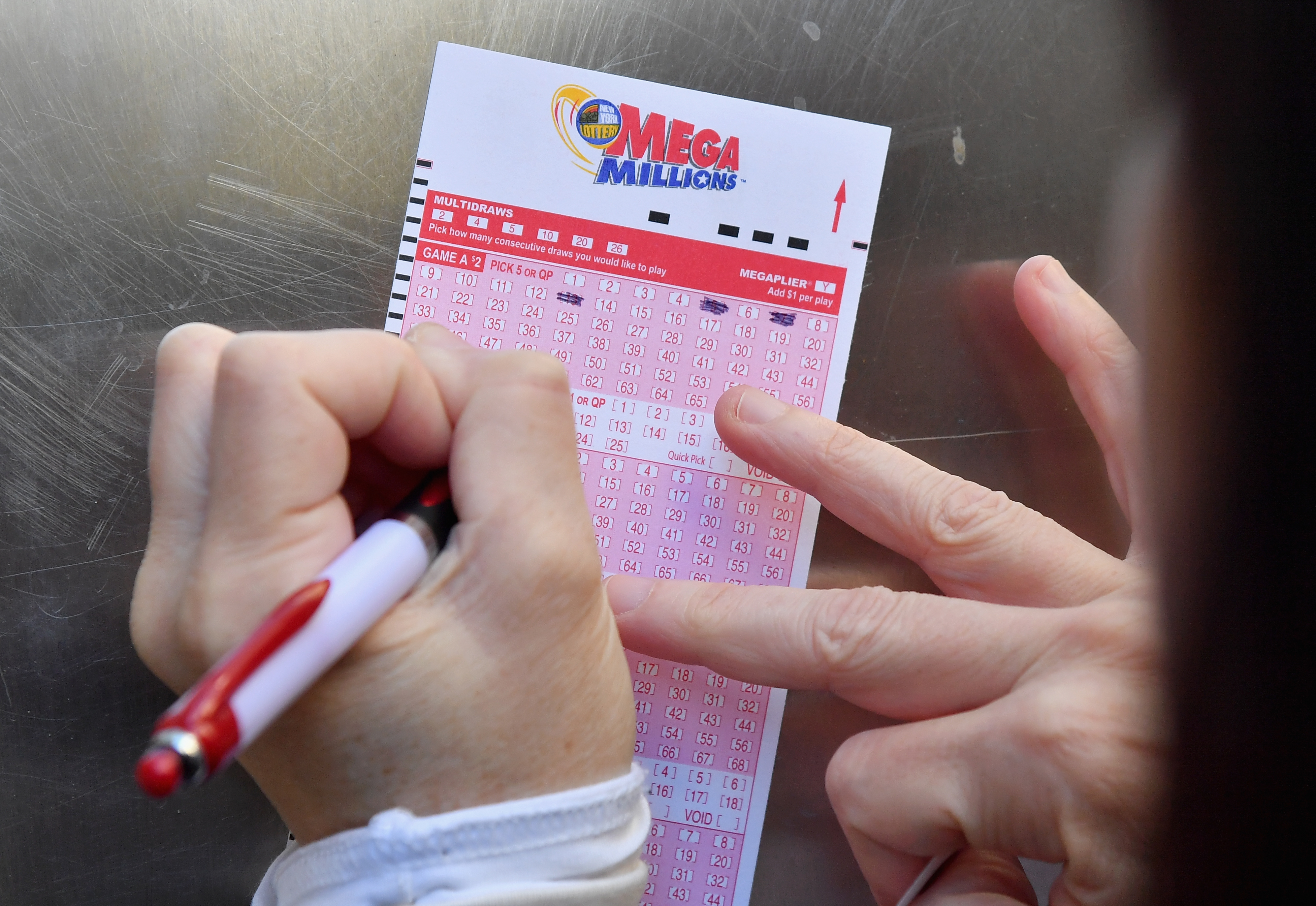 Someone seen filling out a Mega Millions lottery card. 