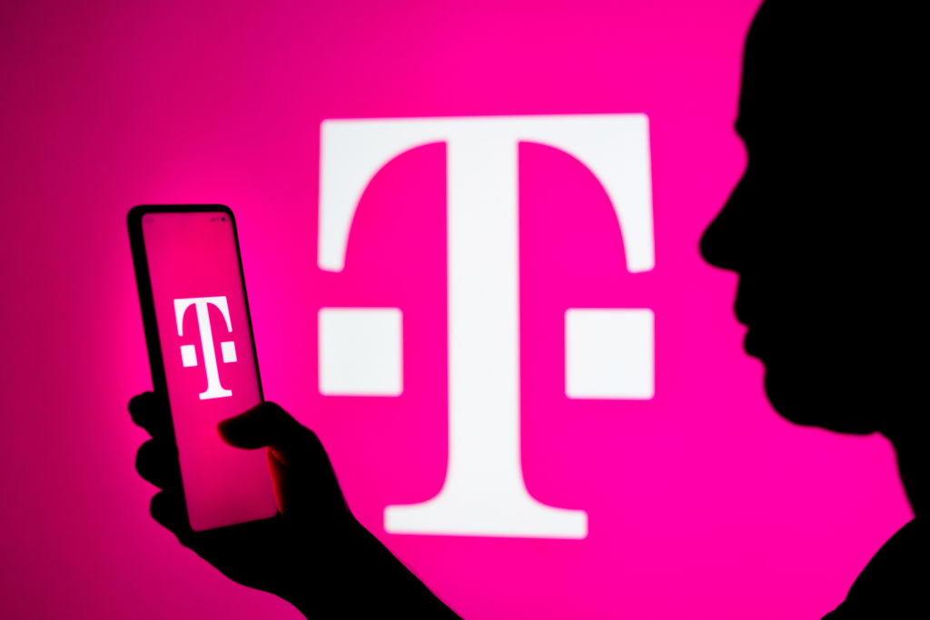 T-Mobile logo in background and on phone held by sillouette