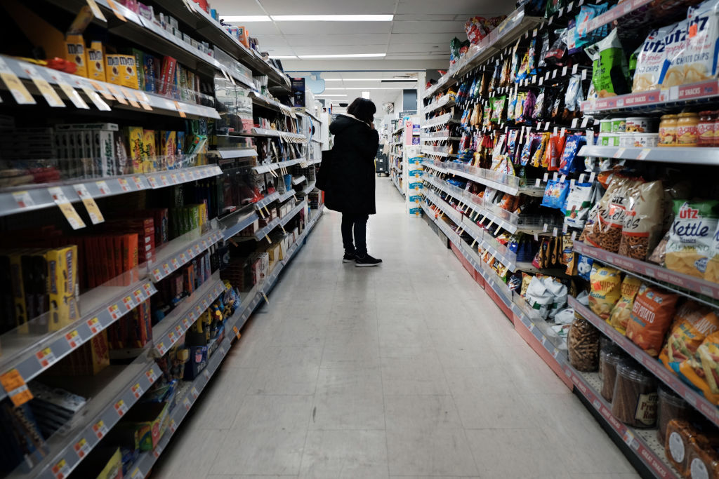 Shopper staring at shelves in grocery store.