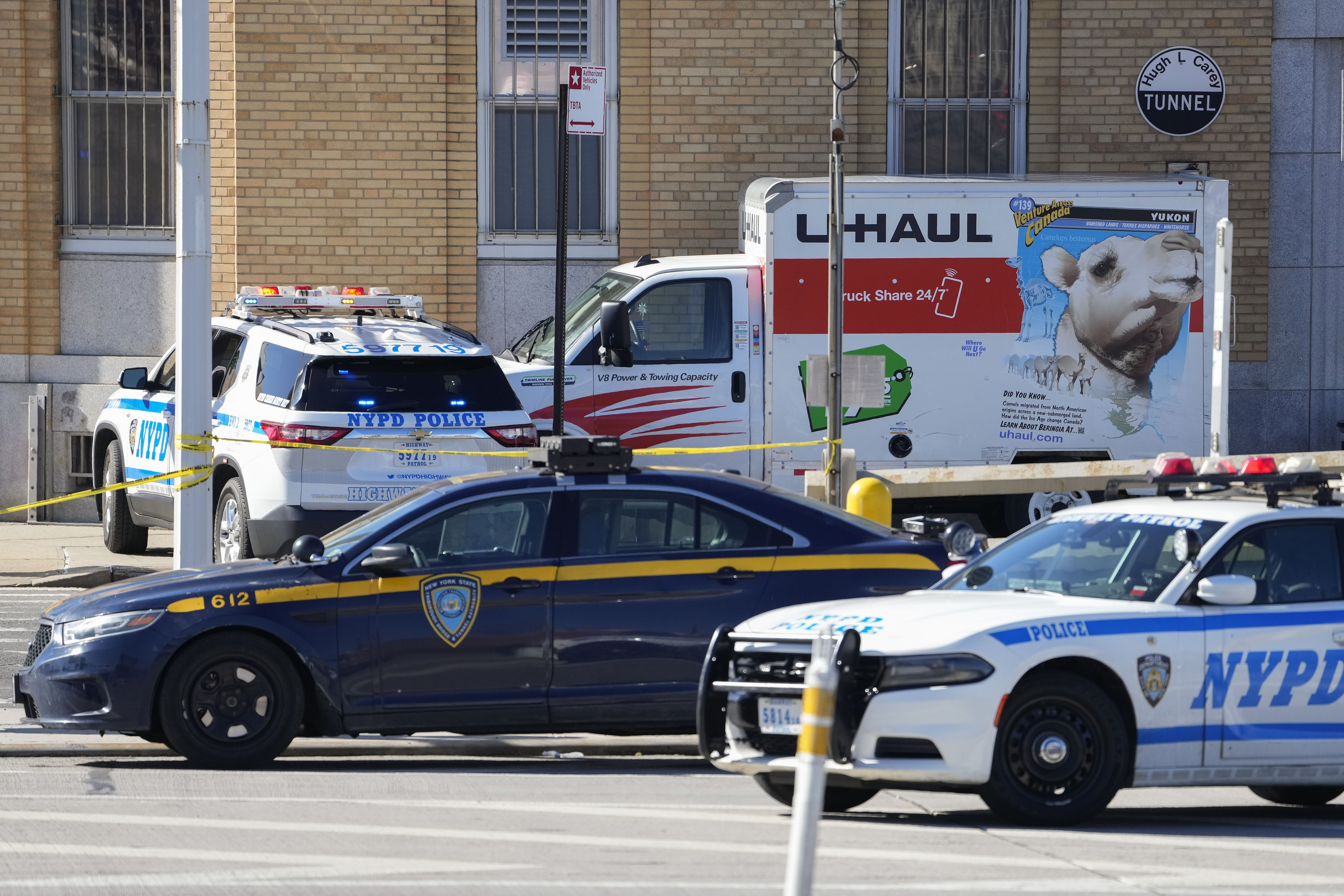 A U-Haul truck surrounded by NYPD vehicles. 