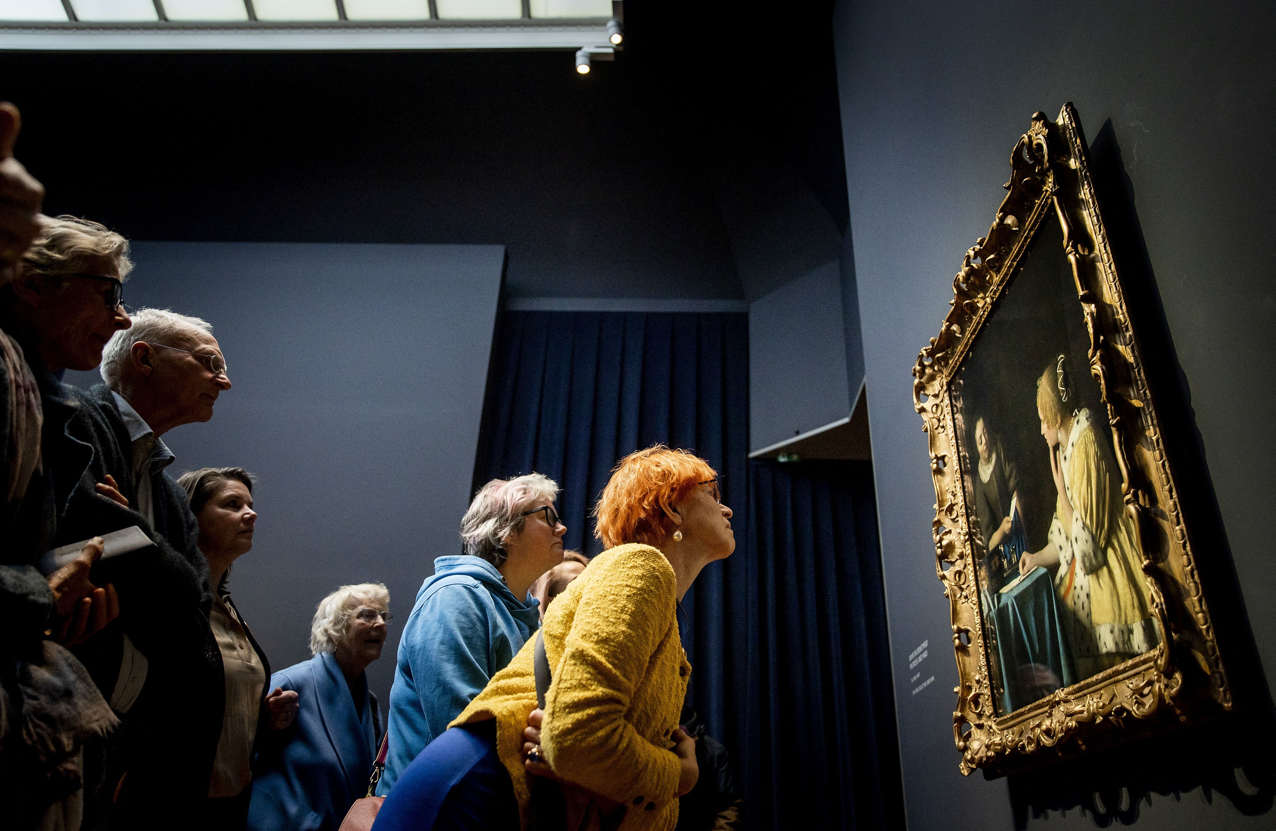 People look at a Vermeer painting on display in Amsterdam.