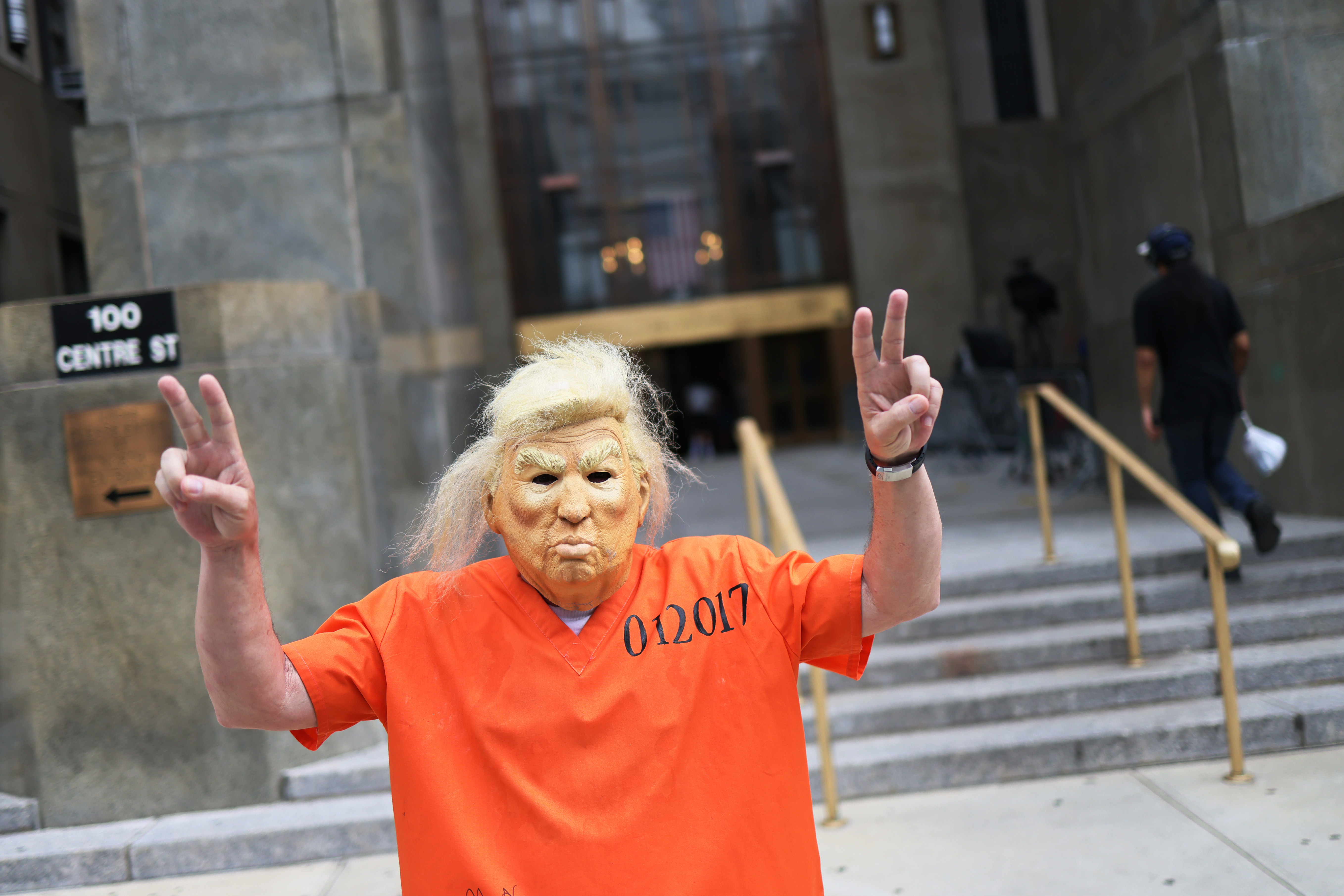 Man in Donald Trump mask wearing prison jumpsuit
